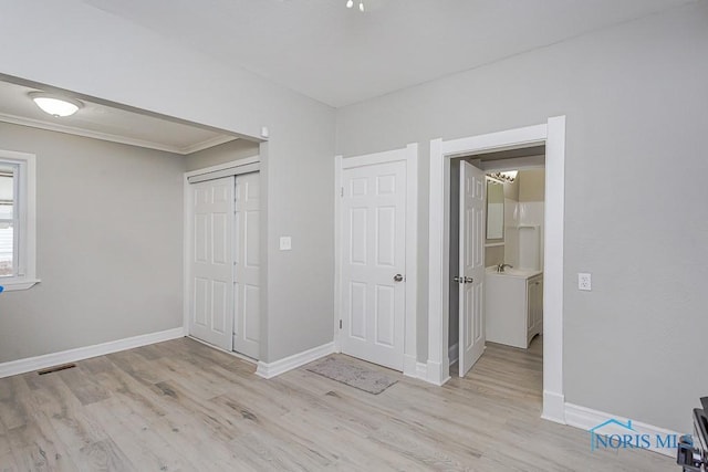 unfurnished bedroom featuring sink, a closet, ornamental molding, and light hardwood / wood-style flooring