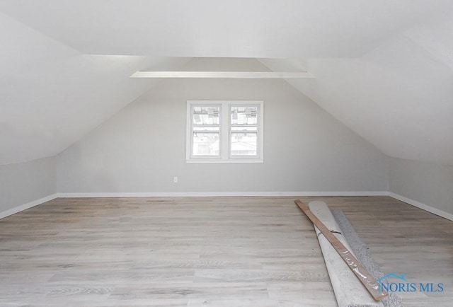 additional living space featuring vaulted ceiling and light hardwood / wood-style flooring