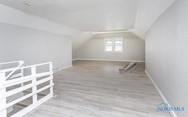 bonus room featuring a baseboard radiator, lofted ceiling, and light hardwood / wood-style floors