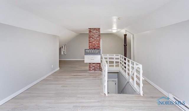 interior space featuring light wood-type flooring, vaulted ceiling, and baseboard heating