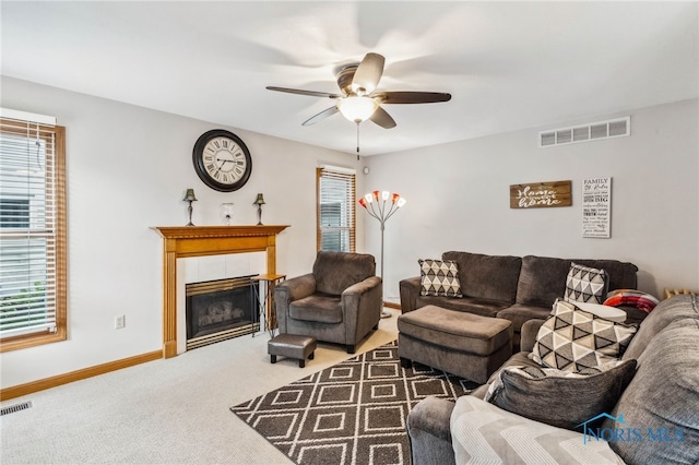 living room featuring carpet, ceiling fan, and a tile fireplace