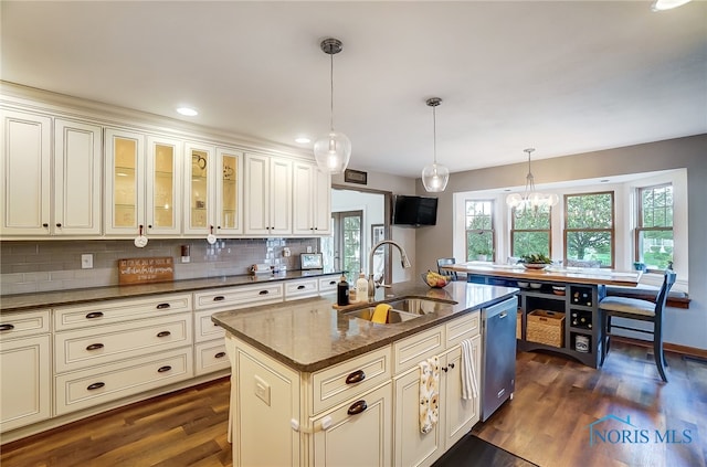 kitchen with stainless steel dishwasher, hanging light fixtures, dark hardwood / wood-style flooring, sink, and a center island with sink