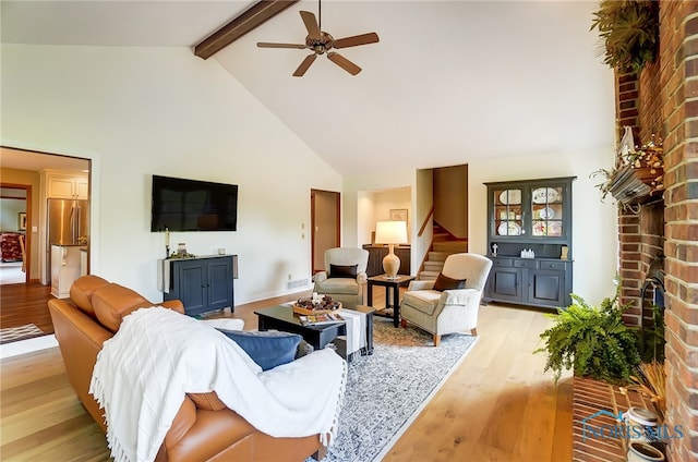 living room featuring ceiling fan, high vaulted ceiling, brick wall, beam ceiling, and light hardwood / wood-style flooring