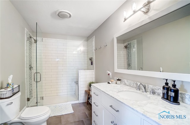 bathroom with vanity, walk in shower, tile patterned flooring, and toilet