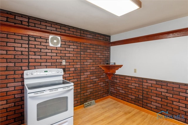 kitchen featuring brick wall and electric stove