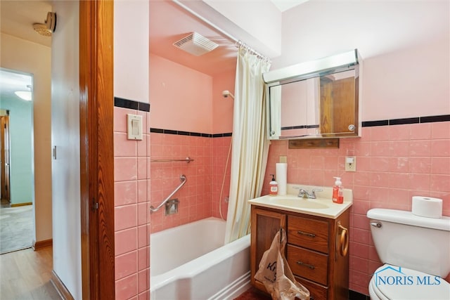 full bathroom with vanity, wood-type flooring, tile walls, shower / bath combo with shower curtain, and toilet