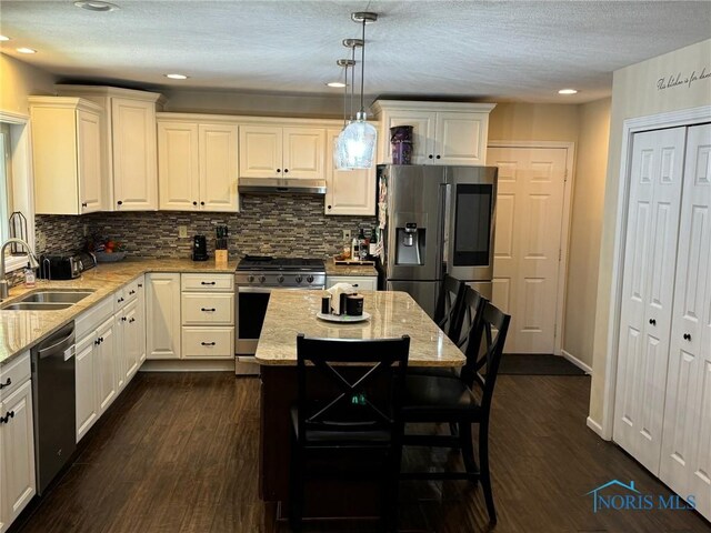 kitchen featuring pendant lighting, sink, a center island, light stone counters, and stainless steel appliances