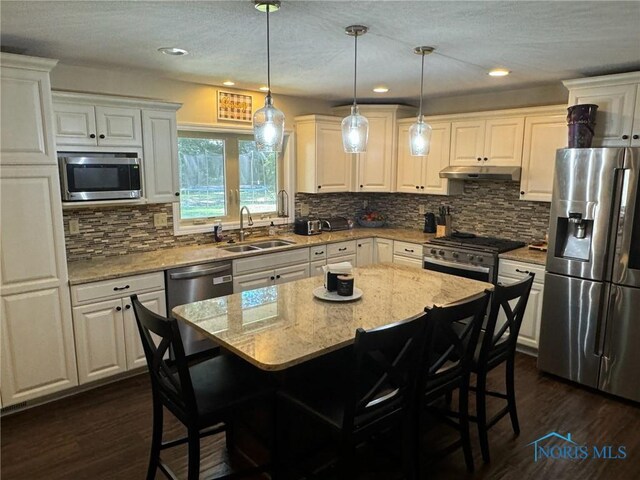 kitchen with light stone counters, stainless steel appliances, a breakfast bar area, and a kitchen island