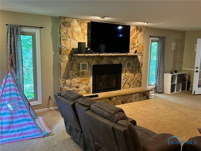 carpeted living room with a stone fireplace and a textured ceiling