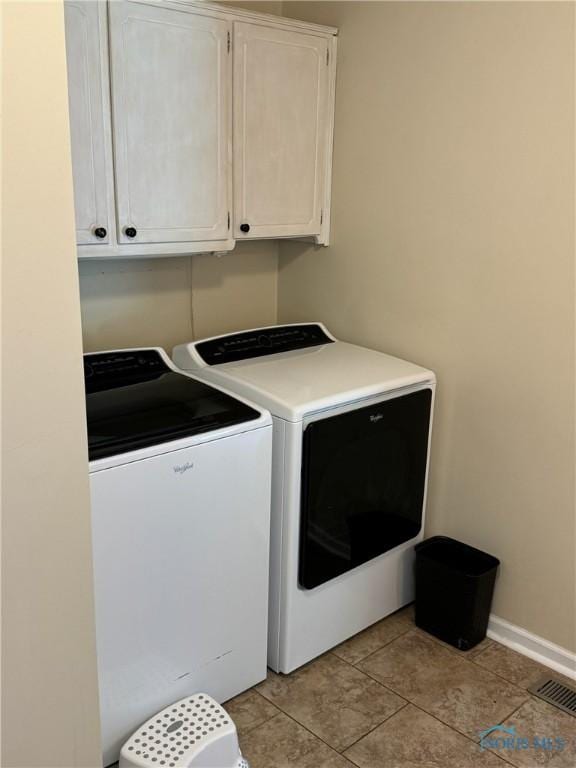 washroom with cabinet space, baseboards, visible vents, and washer and dryer