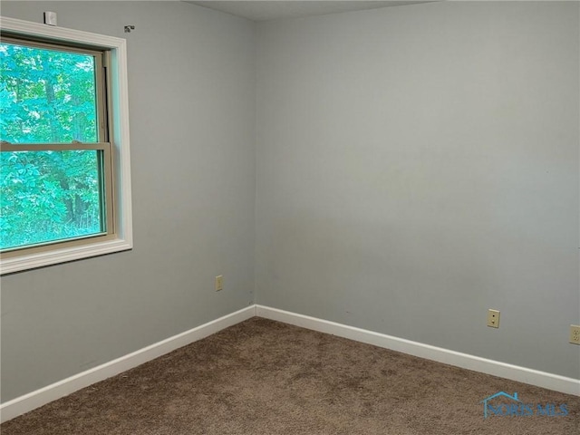 spare room featuring carpet and baseboards