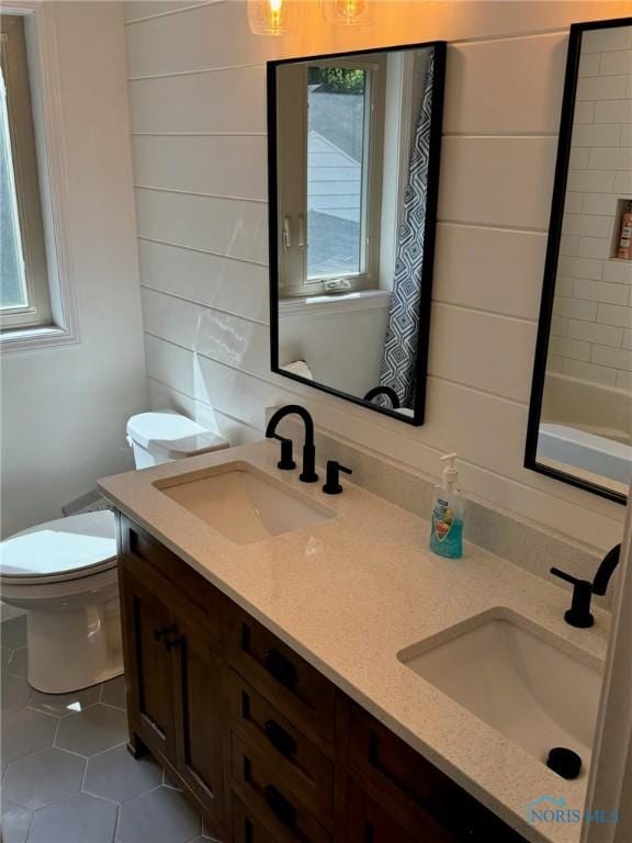 full bath with a sink, toilet, and double vanity