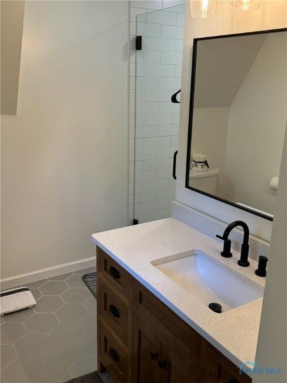 full bathroom with a shower stall, vanity, and baseboards