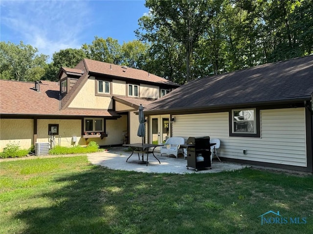 rear view of property with roof with shingles, central AC unit, a lawn, and a patio area