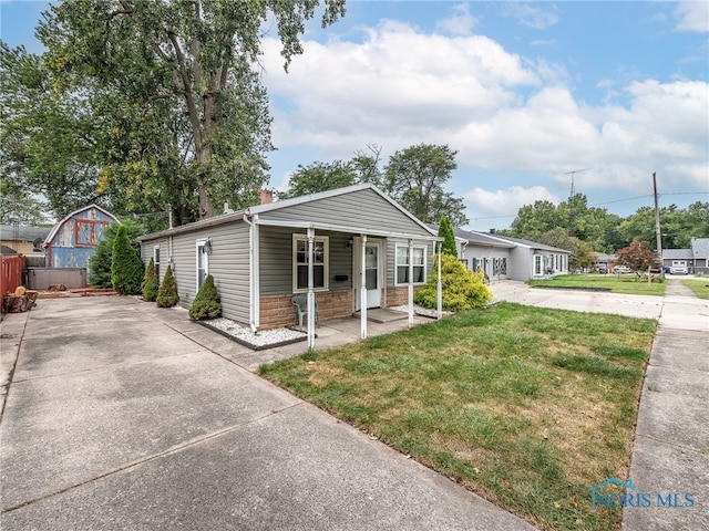 bungalow featuring a chimney, covered porch, stone siding, driveway, and a front lawn