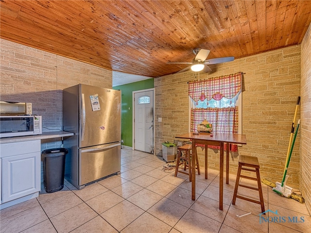 kitchen with light tile patterned flooring, ceiling fan, stainless steel refrigerator, and wooden ceiling