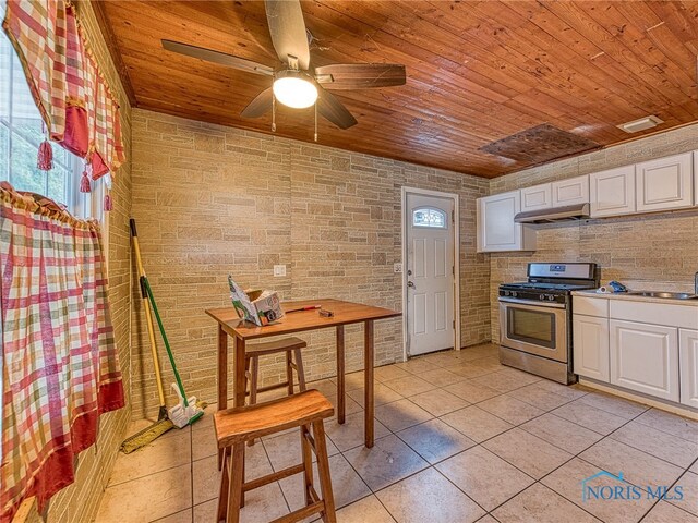 kitchen featuring stainless steel range with gas stovetop, white cabinets, wooden ceiling, and light tile patterned flooring