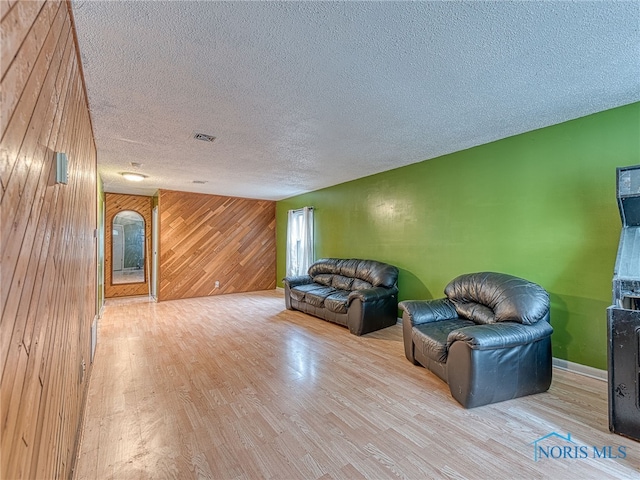 living room featuring wood walls, hardwood / wood-style flooring, and a textured ceiling