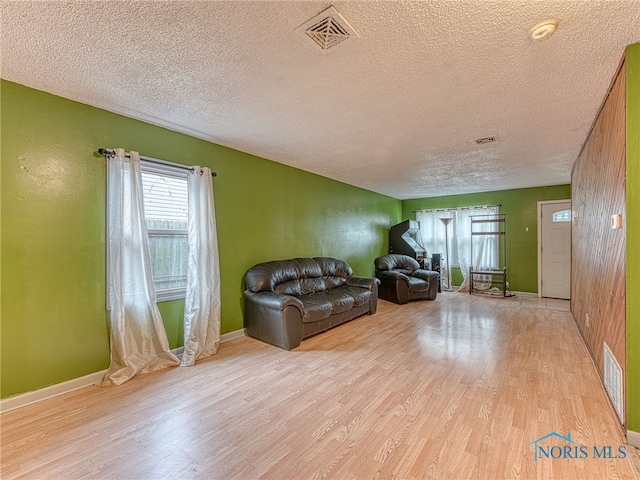 living room featuring light wood-type flooring and a textured ceiling