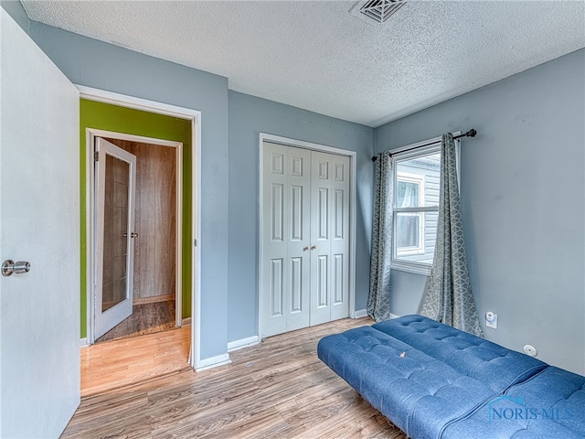 bedroom featuring a textured ceiling, wood-type flooring, and a closet