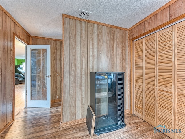 unfurnished living room featuring a textured ceiling, hardwood / wood-style flooring, and wooden walls