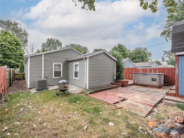 back of house with a hot tub, central air condition unit, a yard, and a deck