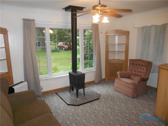 living area featuring a wood stove and ceiling fan