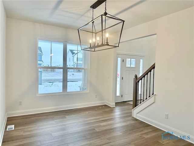 entryway featuring visible vents, baseboards, wood finished floors, stairs, and a chandelier