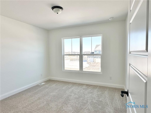 empty room featuring light colored carpet, visible vents, and baseboards