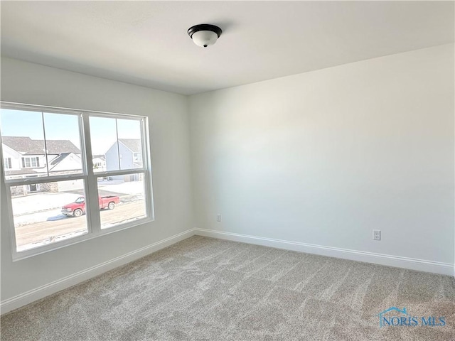 spare room with light carpet and baseboards