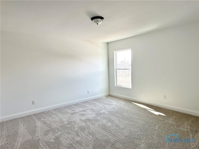 spare room featuring carpet floors and baseboards