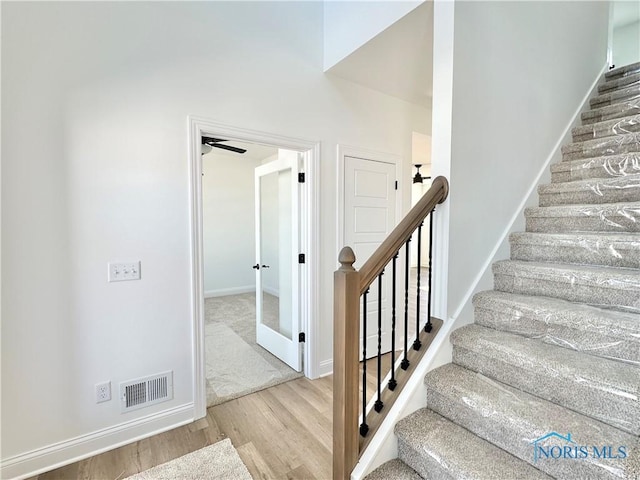 staircase with baseboards, visible vents, and wood finished floors