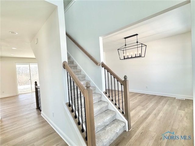 stairway featuring a chandelier, recessed lighting, baseboards, and wood finished floors