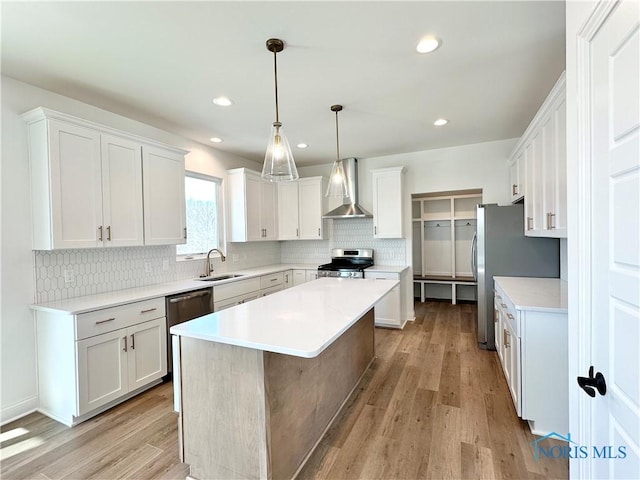 kitchen with white cabinets, wall chimney exhaust hood, appliances with stainless steel finishes, and light countertops