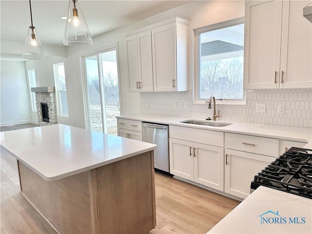 kitchen featuring a sink, white cabinetry, light countertops, hanging light fixtures, and dishwasher