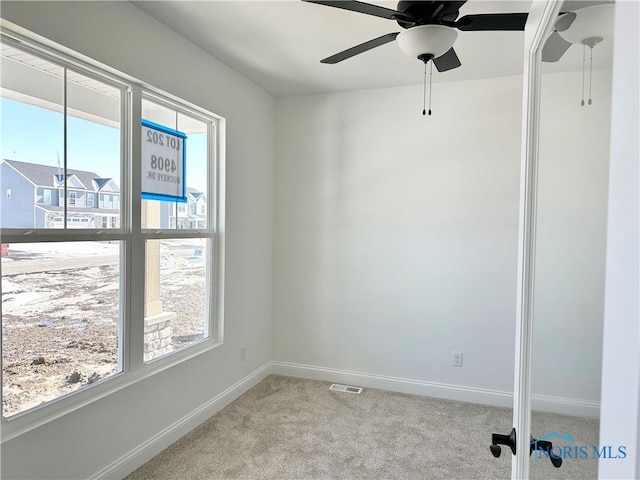 empty room featuring light carpet, plenty of natural light, visible vents, and baseboards