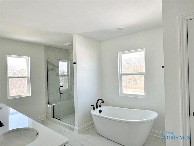 bathroom featuring a shower stall, marble finish floor, a freestanding tub, and baseboards