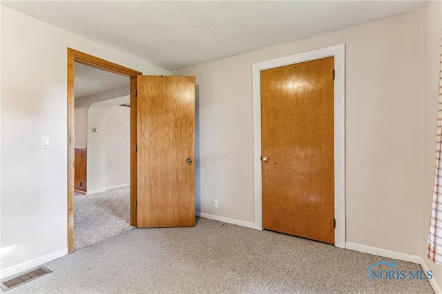 unfurnished bedroom featuring light carpet and a textured ceiling