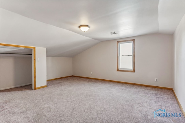 additional living space with lofted ceiling and light carpet