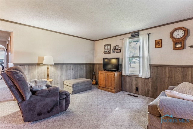 carpeted living room with ornamental molding, wooden walls, and a textured ceiling