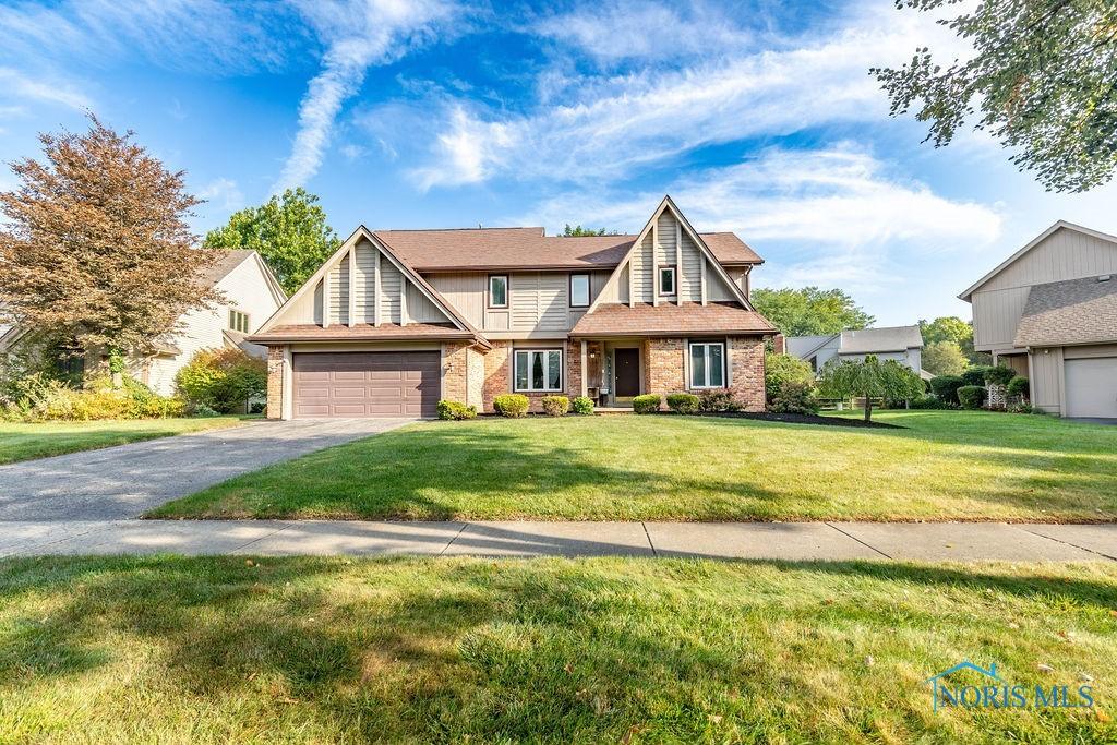 view of front of property featuring a garage, a front yard, brick siding, and driveway