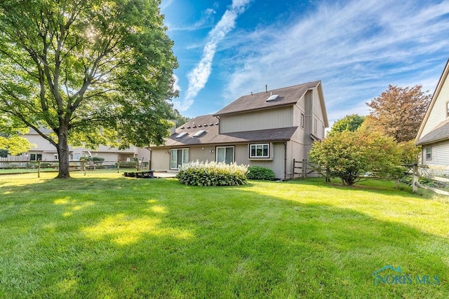 rear view of property with a yard and fence