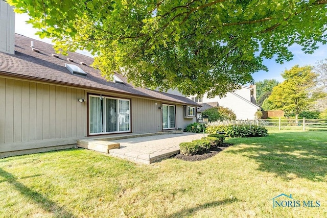 rear view of property featuring fence, a lawn, and a patio