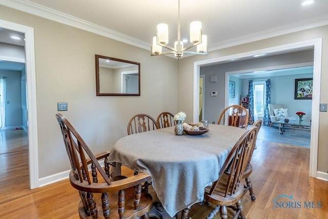 dining room with light wood-style flooring, ornamental molding, a chandelier, and baseboards