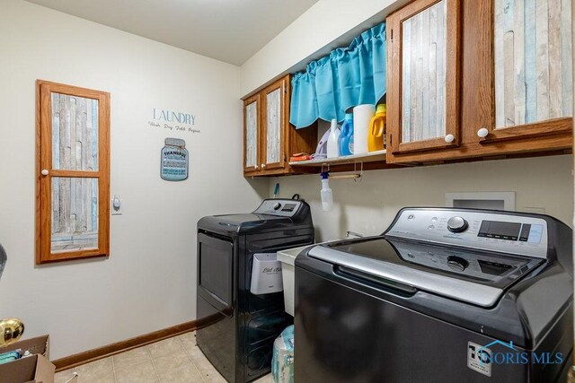 laundry area featuring washing machine and clothes dryer, cabinet space, and baseboards