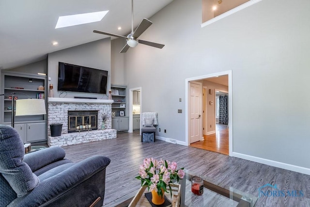 living room featuring a brick fireplace, a ceiling fan, baseboards, and wood finished floors