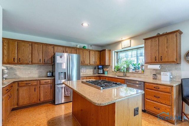 kitchen featuring light floors, appliances with stainless steel finishes, brown cabinets, and a sink