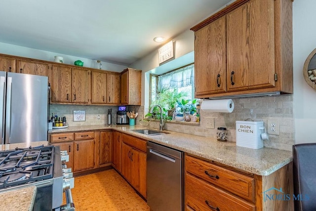 kitchen with stainless steel appliances, tasteful backsplash, brown cabinetry, and a sink