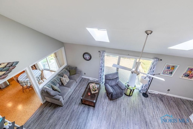 living area featuring lofted ceiling with skylight, baseboards, a wealth of natural light, and wood finished floors