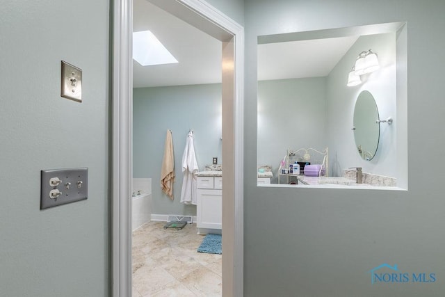 full bath featuring a bath, a skylight, and vanity